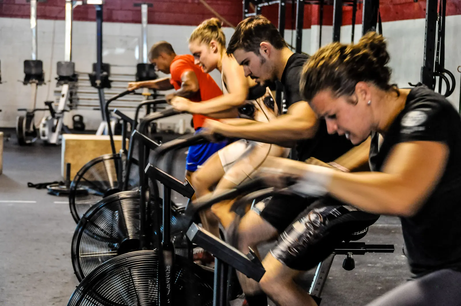 Cours de CrossFit dans une autre salle : des athlètes à fond sur des air bikes (photo d'illustration)
