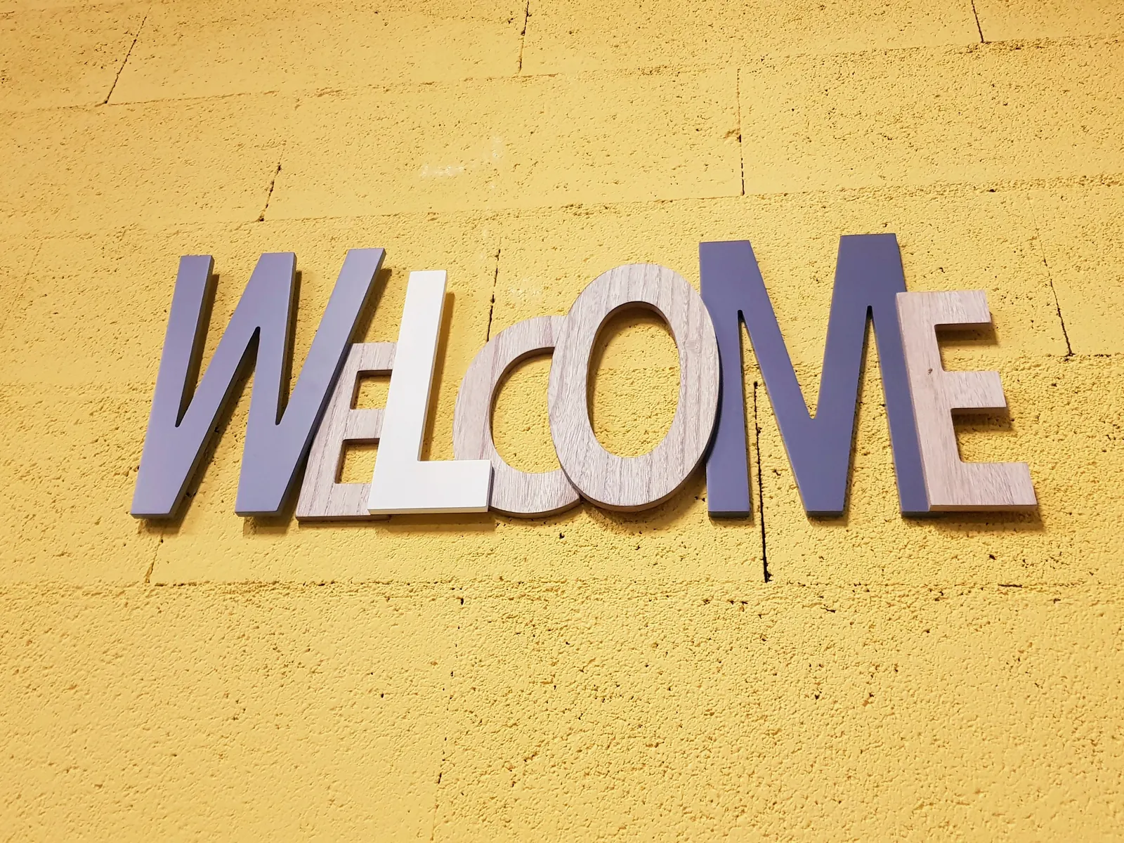 Lettres « WELCOME » sur le mur jaune de la box